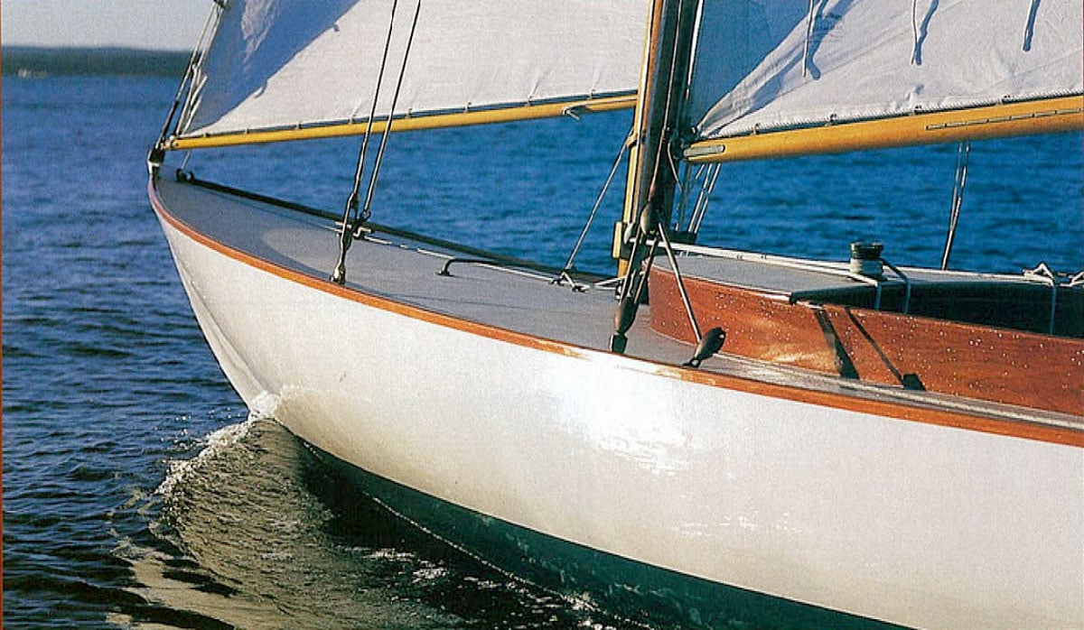 Bow of a wooden sailboat on the water.