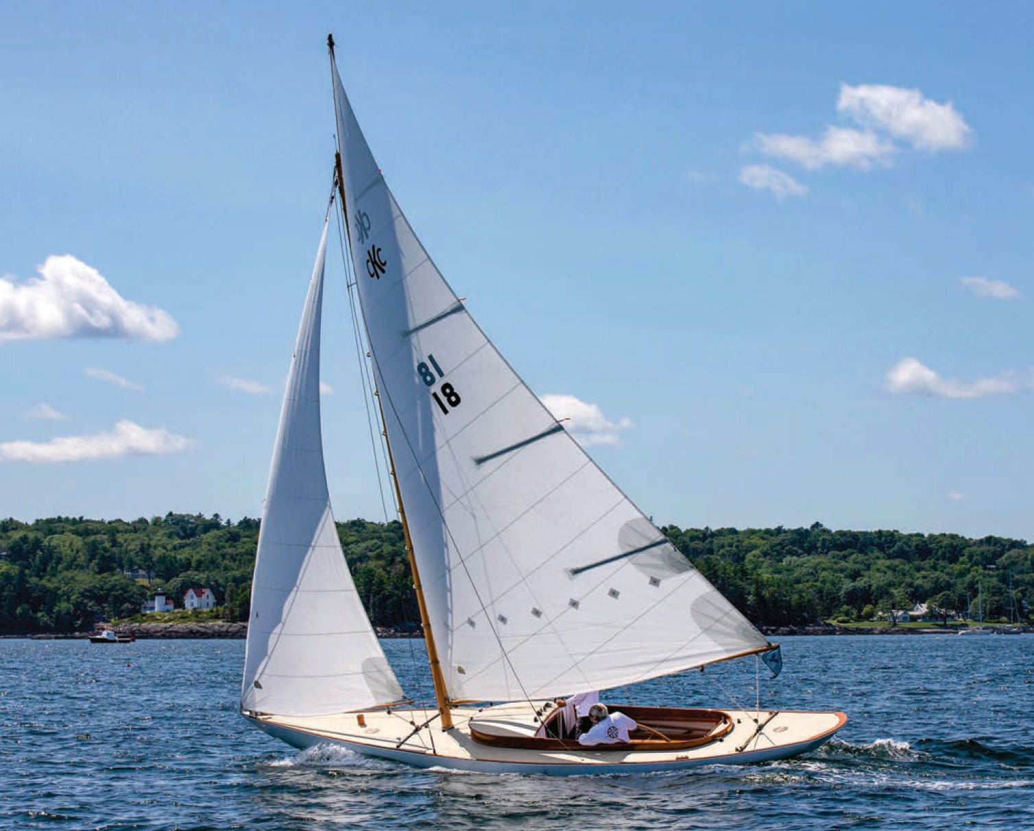 Camden class knockabout sloop sailing under a blue sky.