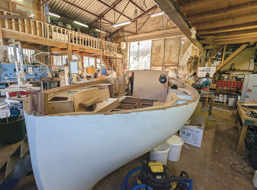 Sail and engine powered yacht under construction in a boat shop.